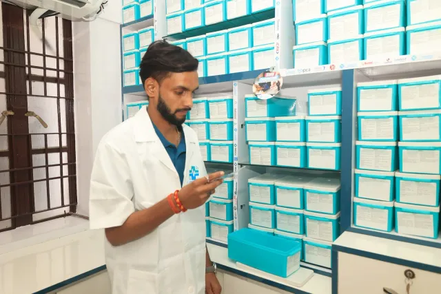 Behind the counter, a team member checks an item beside the storage drawers. — Juran Chapra, Muzaffarpur