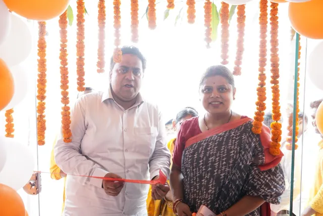 A ribbon-cutting moment against a backdrop of floral decorations. — Godhna Road