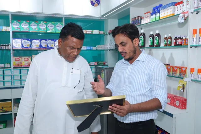 Guests take a closer look at a framed certificate together. — Simrahi Bazar