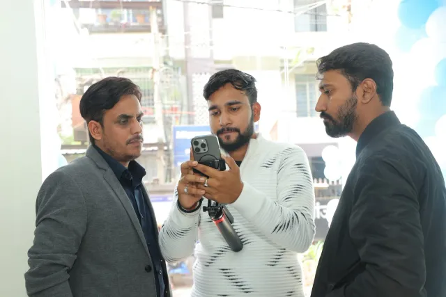 A phone captures another opening-day moment between conversations. — Gardanibagh