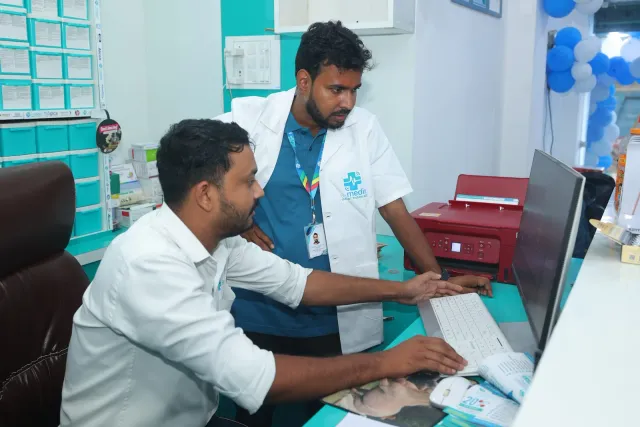 A candid moment of teamwork around the pharmacy computer. — Ashiana Nagar