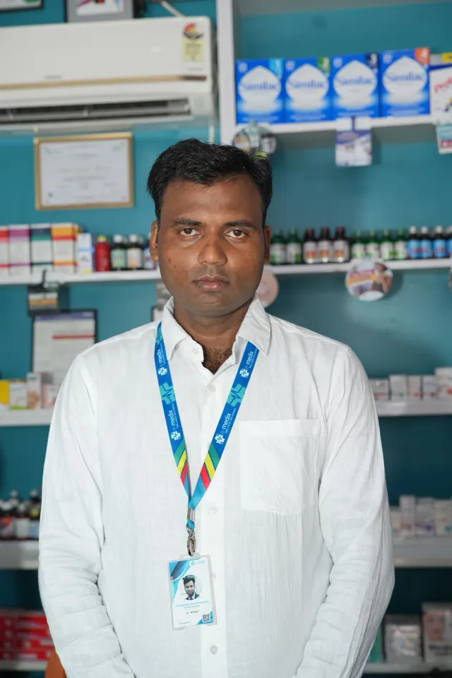 A team portrait against the pharmacy's familiar aqua shelves. — Balua, Motihari