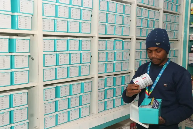 A team member checks a pack beside the storage drawers. — Ramnagri Store