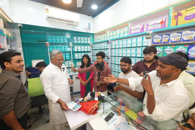 A candid conversation takes place around the pharmacy's computer counter. — Usri Bazar
